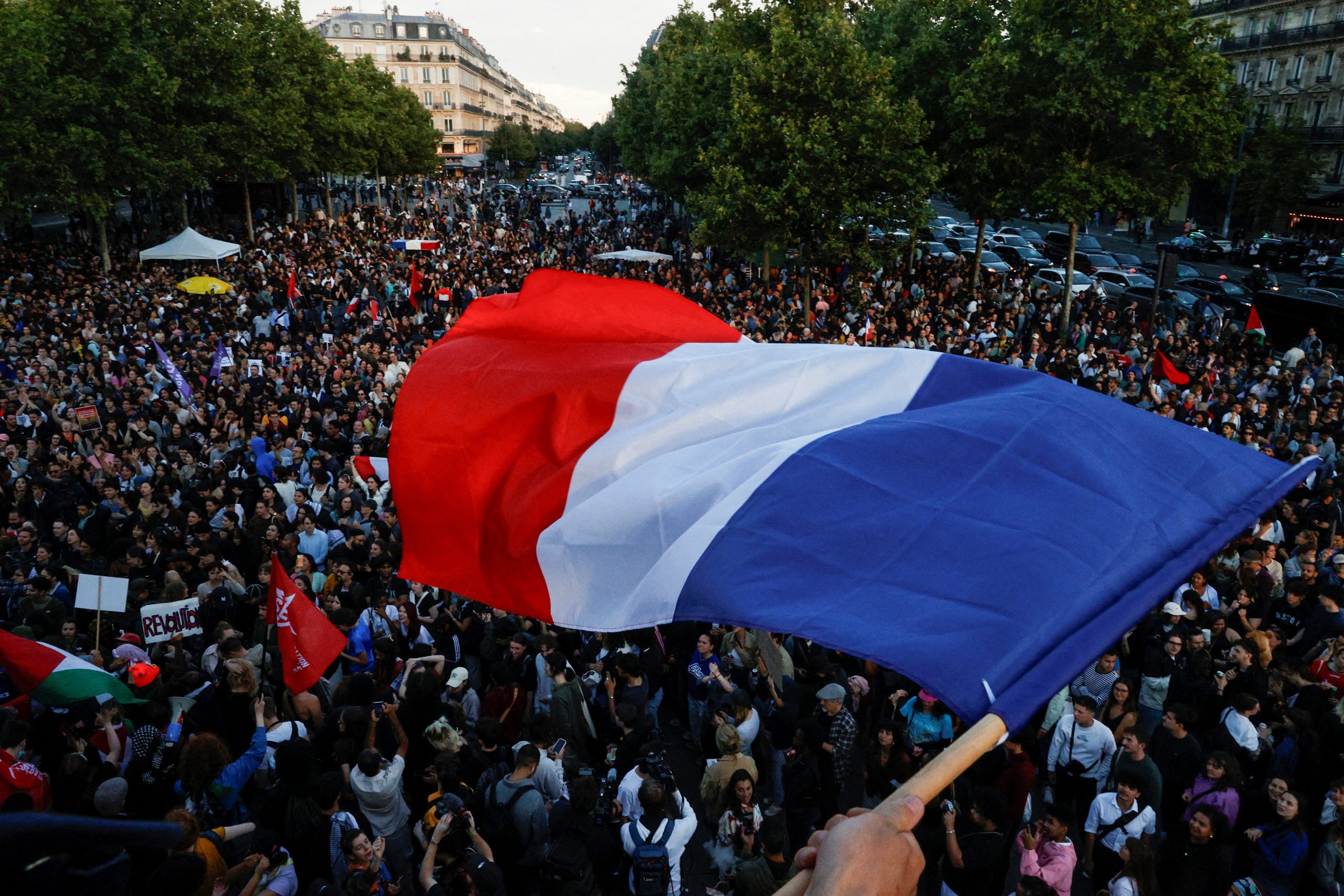 A protester hold a French flag as people gather at the Place de la Republique after partial results in the second round of the early French parliamentary elections, in Paris, France, July 7, 2024. Courtesy:https://icds.ee/en/french-parliamentary-elections-what-is-next-for-the-country-and-what-it-means-on-the-international-stage/